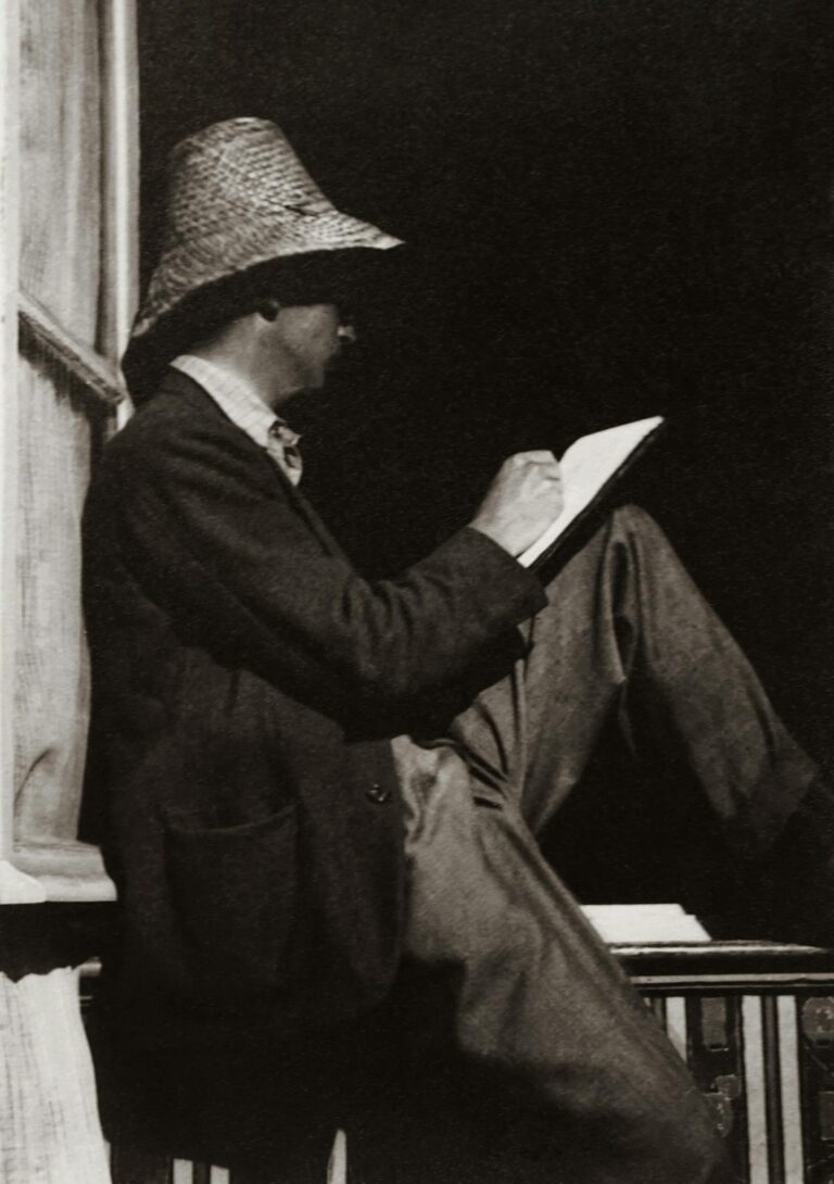 Man Writing On Notebook While Sitting On Wooden Handrail